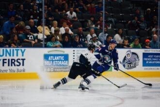 Intense ice hockey game action with players competing for the puck.
