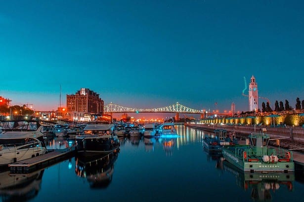 Twilight at Montreals Old Port with boats and cityscape.