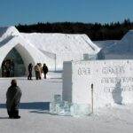 Visitors exploring the entrance of an ice hotel during winter.