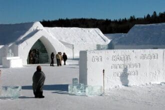 Visitors exploring the entrance of an ice hotel during winter.