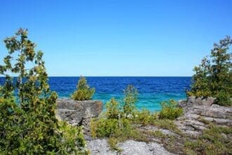 Scenic Tobermory coastline with clear blue waters and rocky shore.