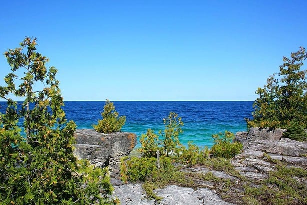 Scenic Tobermory coastline with clear blue waters and rocky shore.