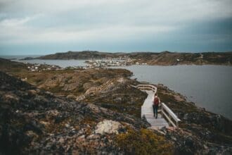 Woman walking on scenic coastal trail in Fogo Island, Newfoundland.